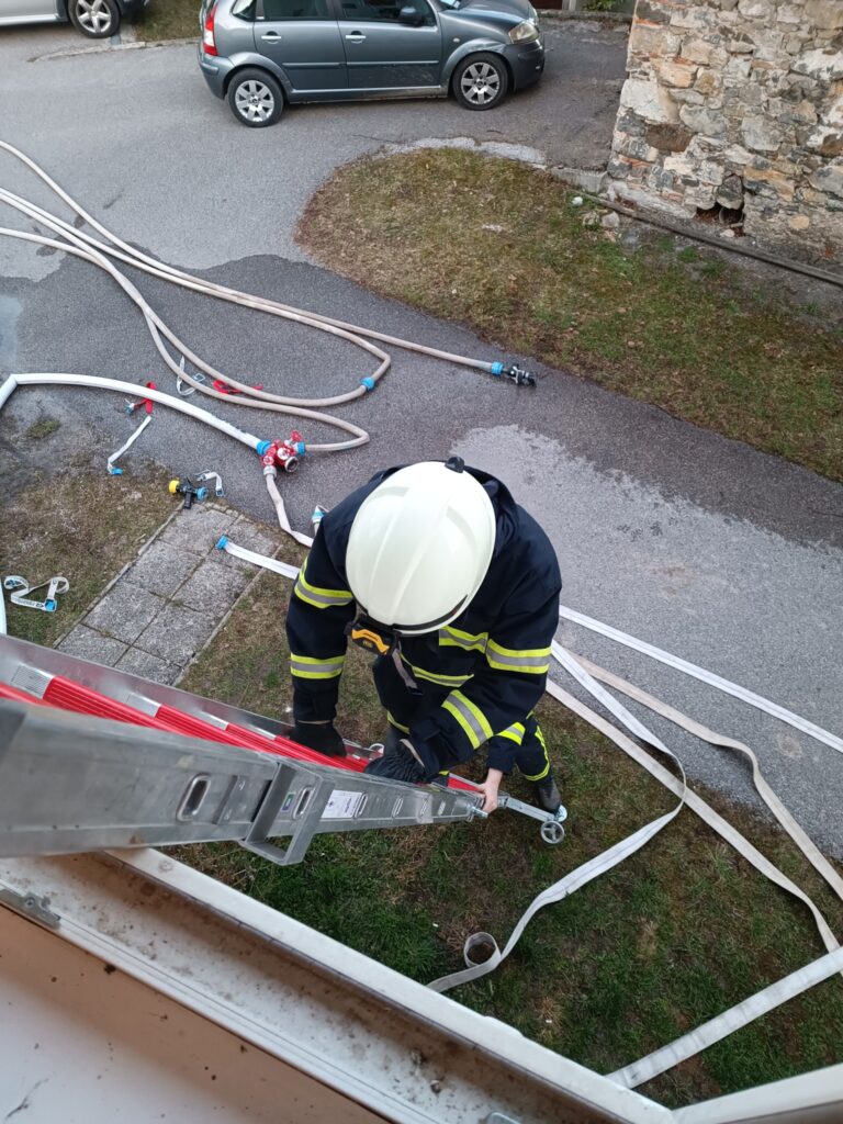 Gasilec se vzpenja po lestvi na rednih mesečnih vajah v marcu 2025